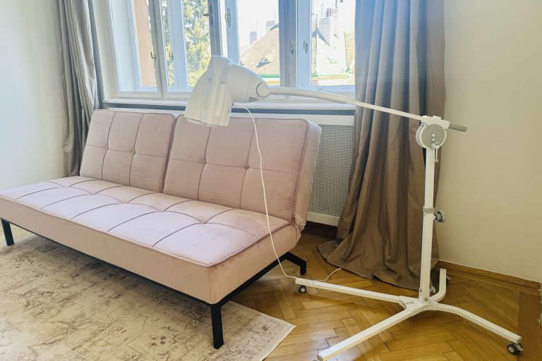 Bioptron PRO1 mit Standstativ neben einem Altrosa-Sofa in einer Wiener Wohnung – persönliches Setting für tägliche Lichttherapie